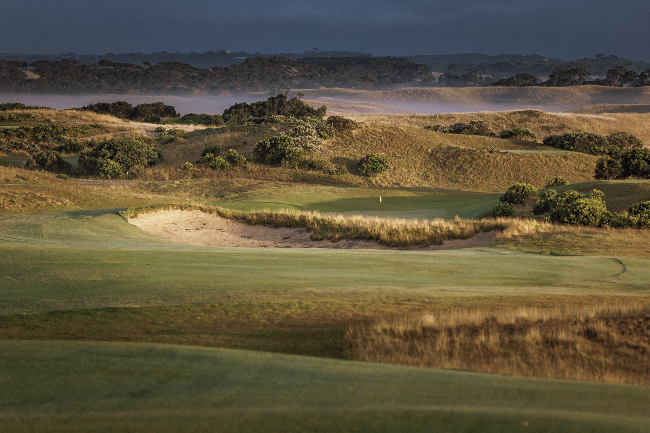 Sprinklers backlit at dawn over the dunes of The National's Gunnamatta course
